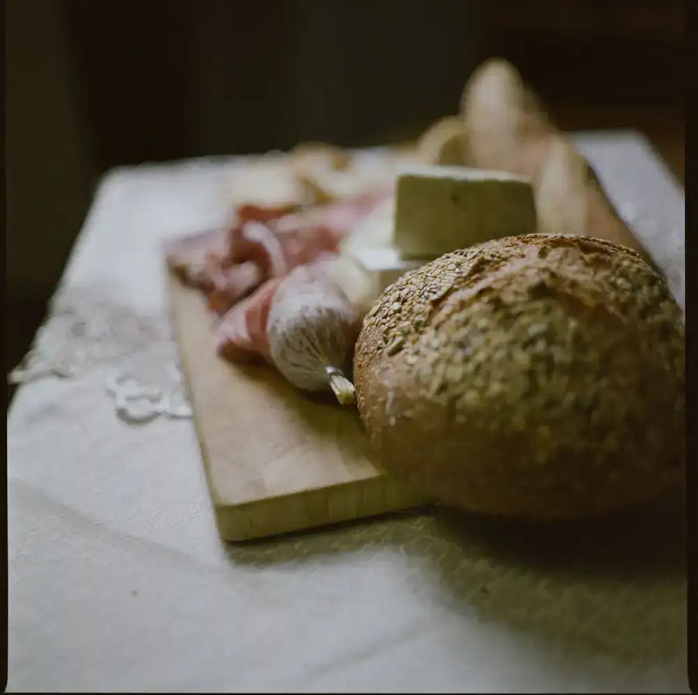 A large wooden board filled with cheeses, cured meats, and fresh bread