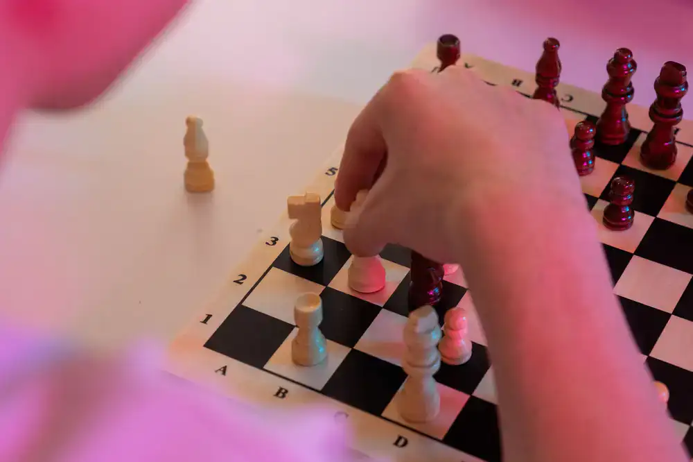Players moving wooden pieces on a complex strategy board game